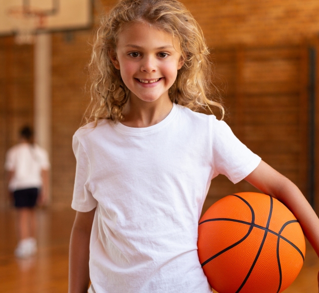 happy-schoolgirl-holding-a-basketball-and-looking-2021-08-28-16-44-10-utc